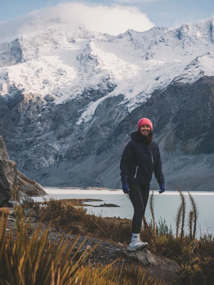 ragazza con cappellino rosa che cammina, sullo sfondo un lago e il Mount Cook innevate
